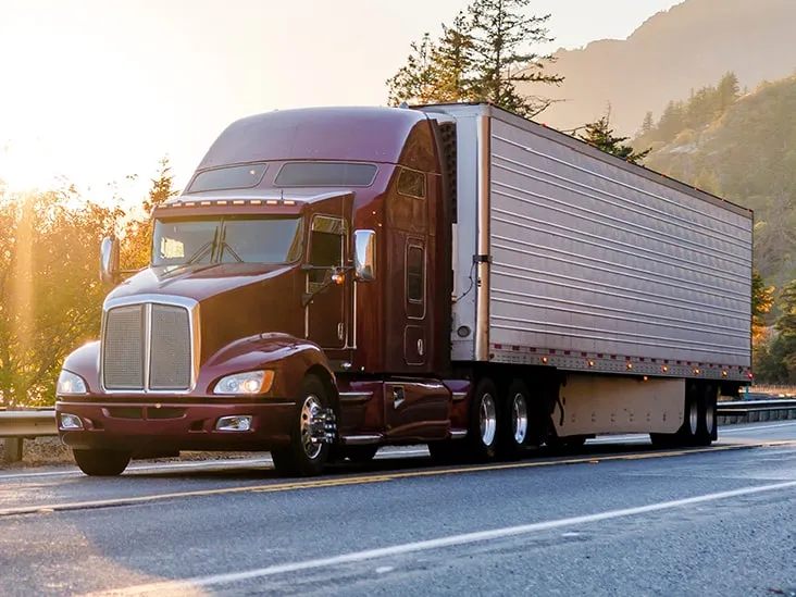 Semi truck driving on a highway at sunset